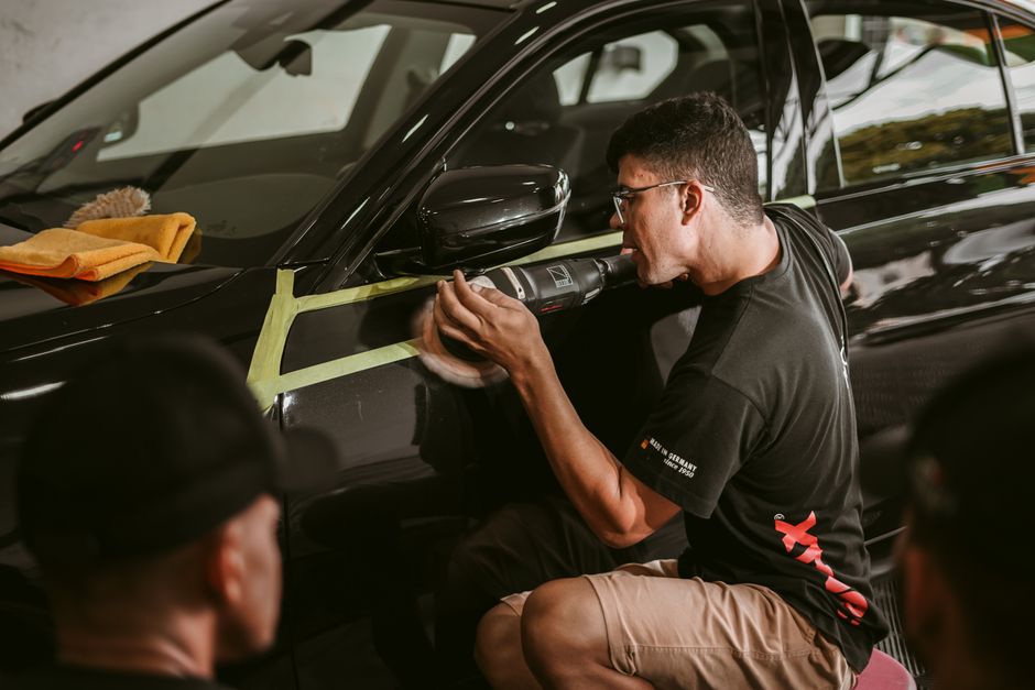 Professional applying ceramic coating to a luxury car exterior